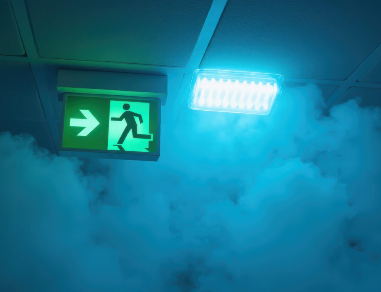 Green illuminated fire exit sign with smoke
